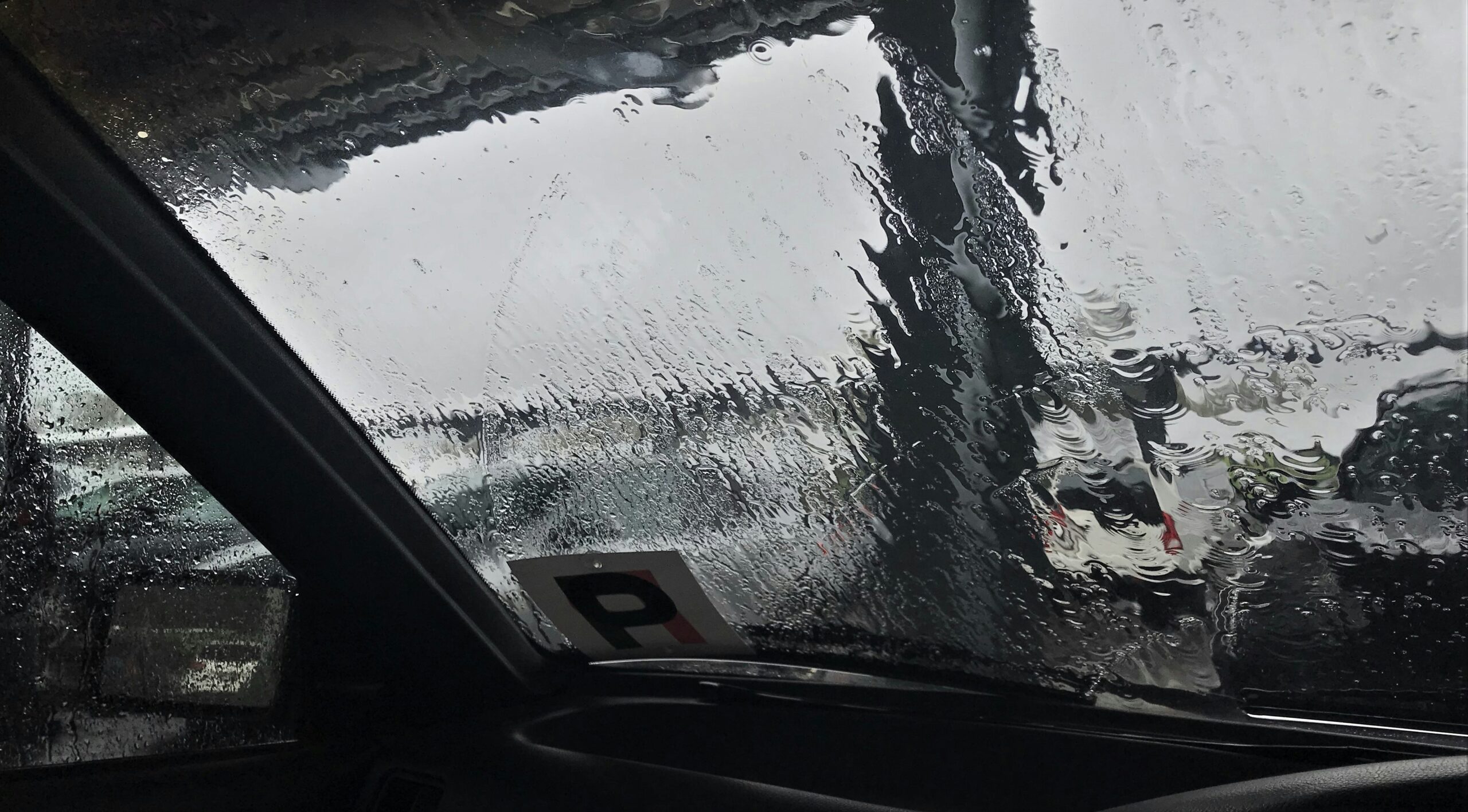 A close-up image of a car windshield damaged by hailstones showing cracks and chips.