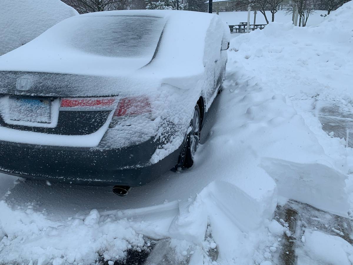 A car safely parked under a hail car shield amidst falling hail